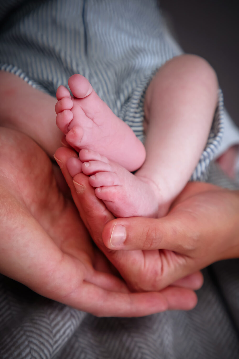 Kleine Babyfüße in den Händen eines Erwachsenen