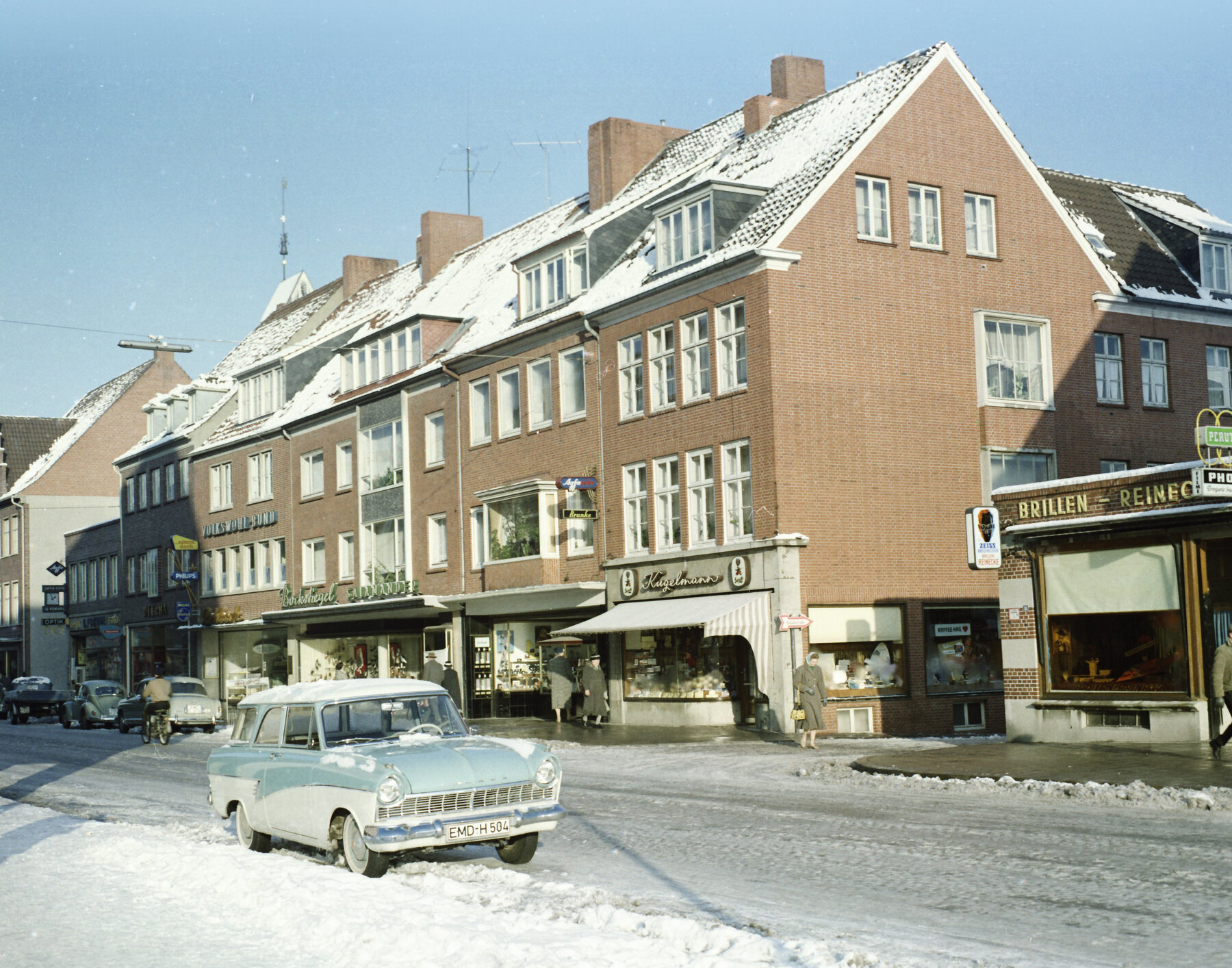 Verschneite Emder Innenstadtstraße im Winter 1966 mit den Geschäften Kugelmann und Brillen Reimer, am Straßenrand ein Opel Rekord Caravan mit Emder Kennzeichen